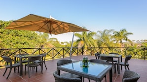 An outdoor patio with wicker furniture, a glass table, and a large umbrella. - San Lameer Villa Rentals One Bedroom Standard 10425 (Southbroom)