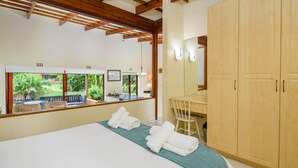 Une chambre d’hôtel avec un grand lit, un bureau et une armoire. Il y a une fenêtre donnant sur un paysage verdoyant.