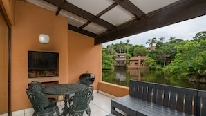 Une terrasse extérieure avec une table et des chaises, un barbecue et une vue sur un lac et la végétation environnante.
