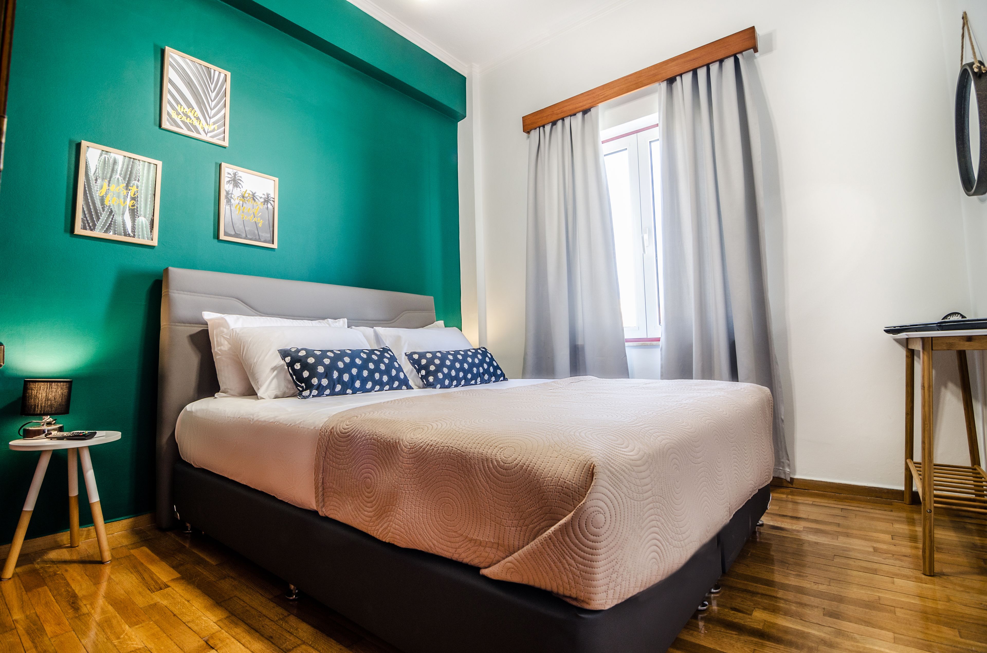 Une chambre bien rangée, avec un grand lit, une petite table de chevet et une fenêtre avec des rideaux.
