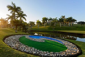 A landscaped garden with a circular water feature, palm trees, and a grassy area. - San Lameer Villa Rentals Three Bedroom Luxury 13908 (Southbroom)