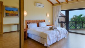 Une chambre spacieuse avec un grand lit, une tête de lit en bois et une vue sur l’extérieur.