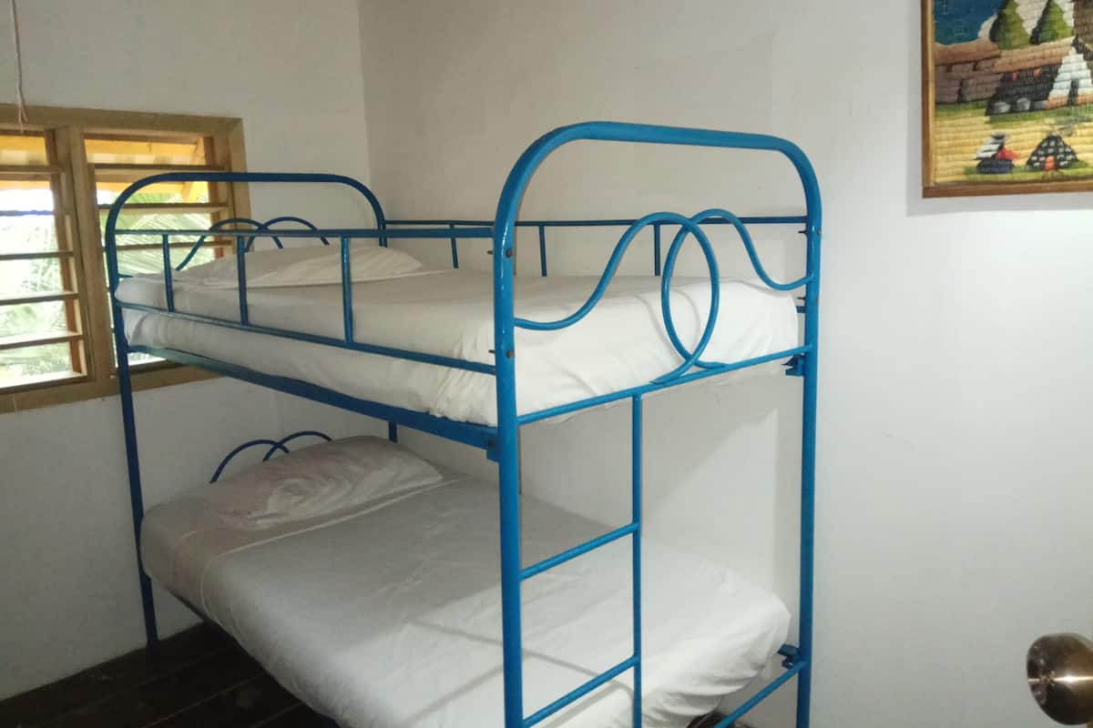 A bunk bed with three levels, a window with wooden frames, and a painting on the wall.