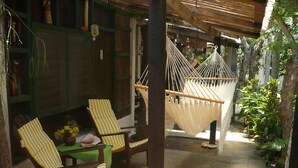 A cozy outdoor seating area with two striped chairs and a table, a hammock, and lush greenery. - Caribbean Coral Inn Tela (Tela)