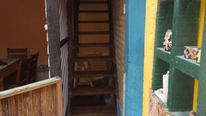 A narrow stairway leading to a lower level, flanked by wooden structures and a green shelf with decorative items. - Caribbean Coral Inn Tela (Tela)