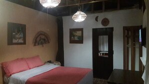 A bedroom with a bed, a nightstand, a hanging light fixture, and a door. - Caribbean Coral Inn Tela (Tela)