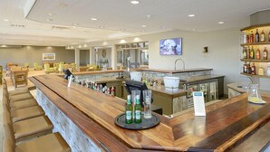 A bar area with a long counter, stools, and a variety of bottles. - San Lameer Villa Rentals Two Bedroom Standard 1928 (Southbroom)