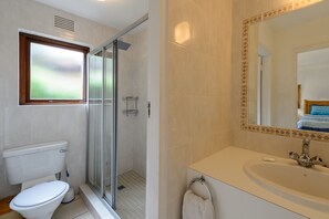 A bathroom with a toilet, a glass-enclosed shower, and a sink with a mirror. - San Lameer Villa Rentals Two Bedroom Standard 1928 (Southbroom)
