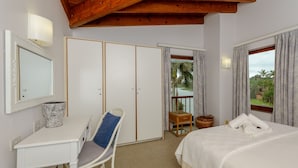 Ein Schlafzimmer mit Bett, Schreibtisch, Stuhl, Kleiderschrank und einem Fenster mit Vorhängen.