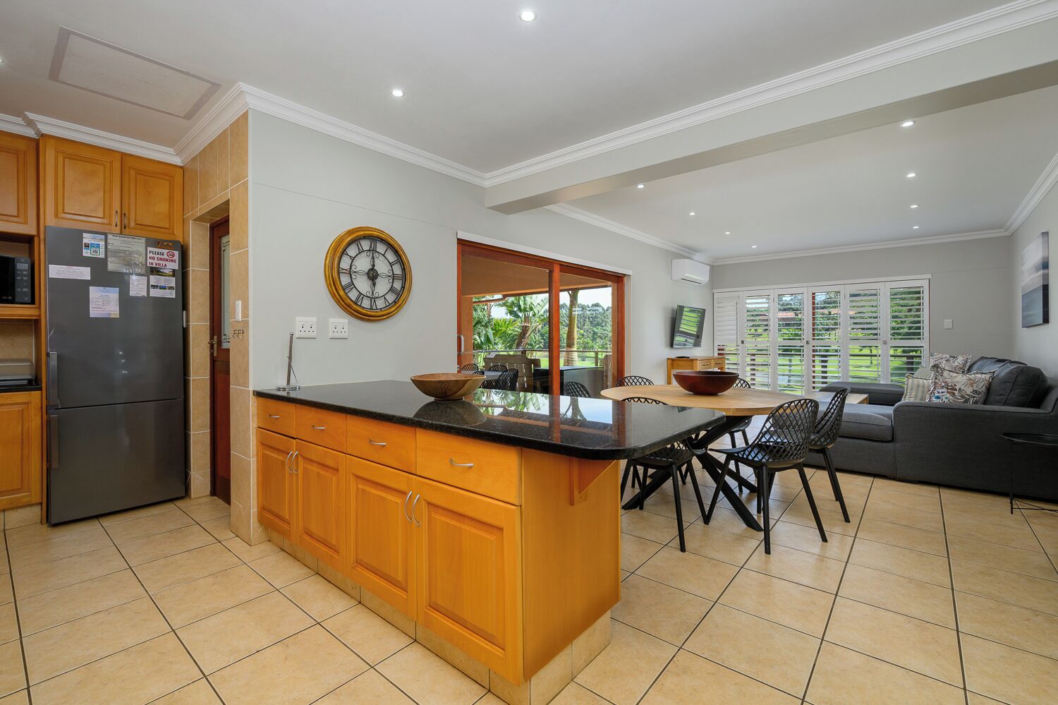 Una cocina moderna con armarios de madera, una isla integrada y un comedor con mesa y sillas.