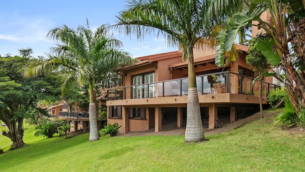 A two-story building with a balcony, surrounded by palm trees and greenery. - San Lameer Villa 10429 (Southbroom)