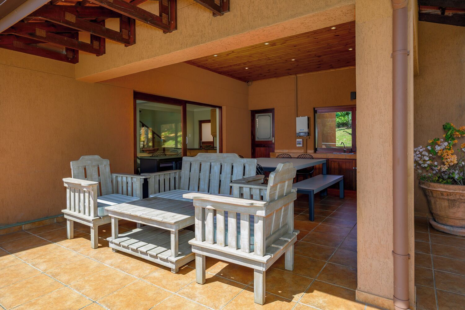 An outdoor patio with wooden furniture, a dining table, and a large planter.