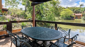 A covered outdoor area with a round table and chairs, overlooking a body of water and lush greenery. - San Lameer Villa Rentals 1909 (Southbroom)