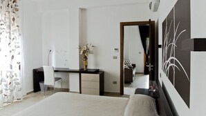A modern hotel room with a bed, a desk, a chair, a dresser, and a mirror. - InStile aparthotel (Ascea)