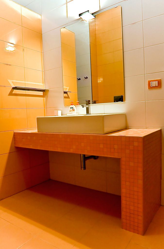 Un baño con lavamanos, espejo y paredes con azulejos.