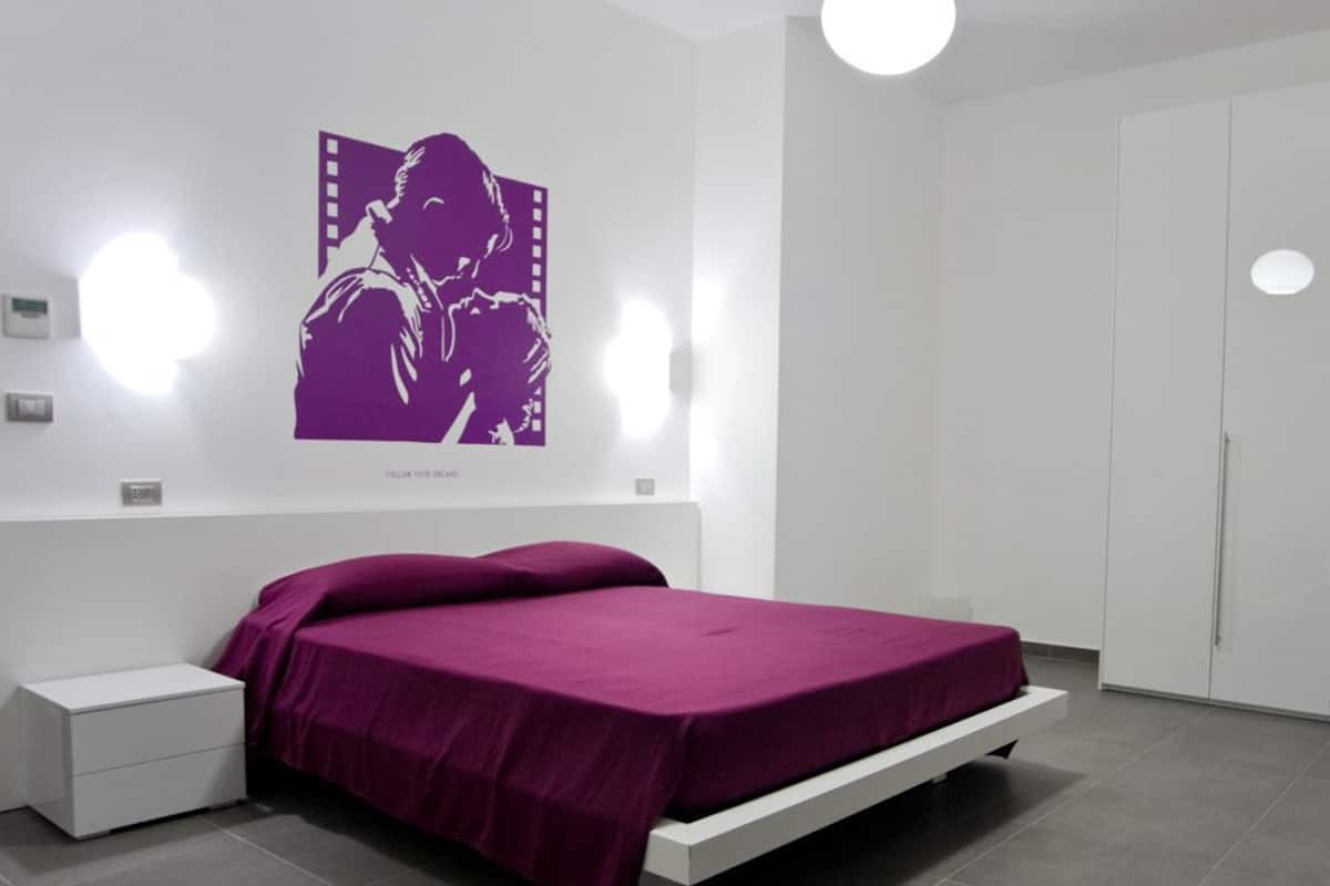 Un dormitorio moderno con cama, mesita de noche, armario y un cartel en la pared.