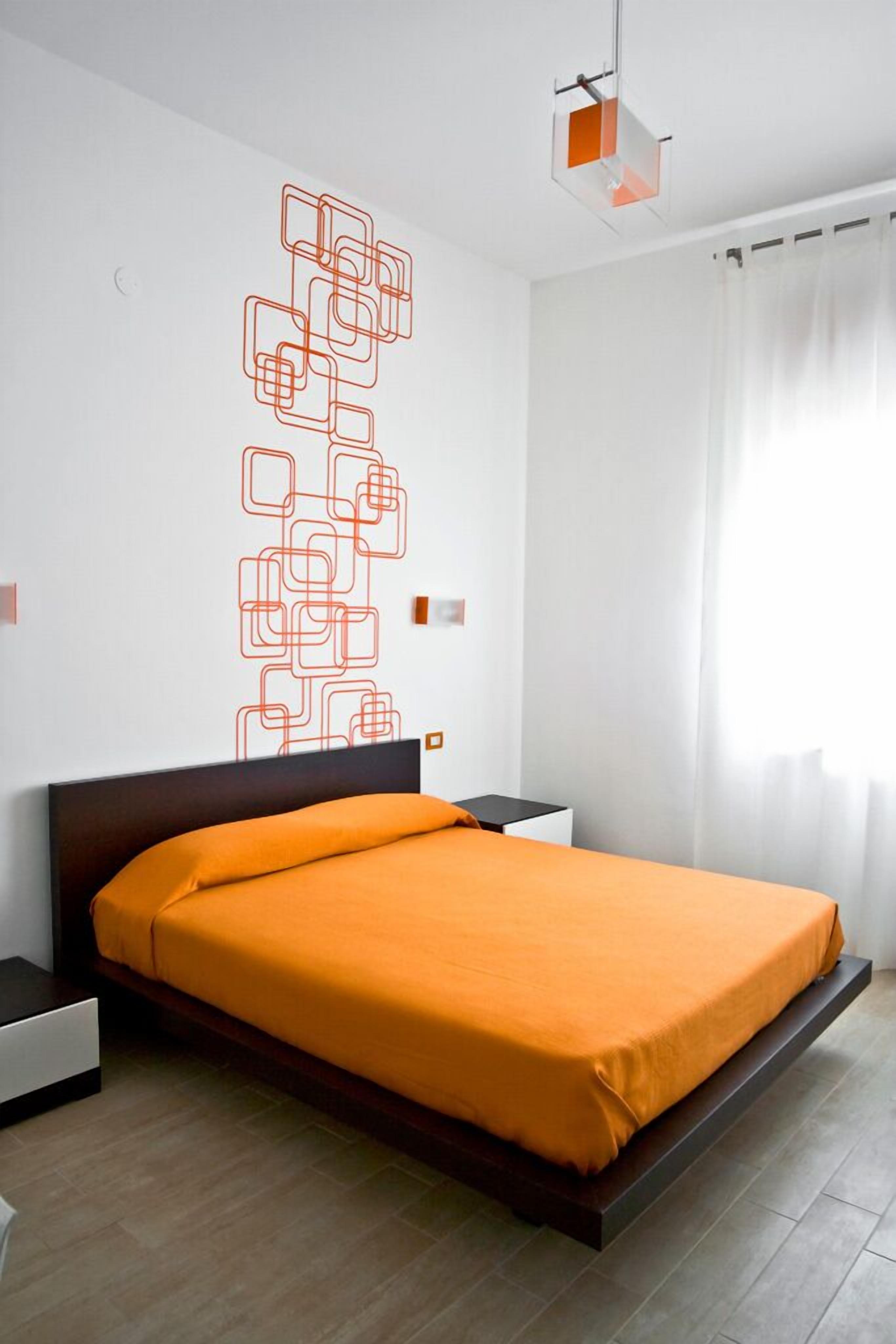 A modern bedroom with a bed, nightstands, and a geometric wall decoration.