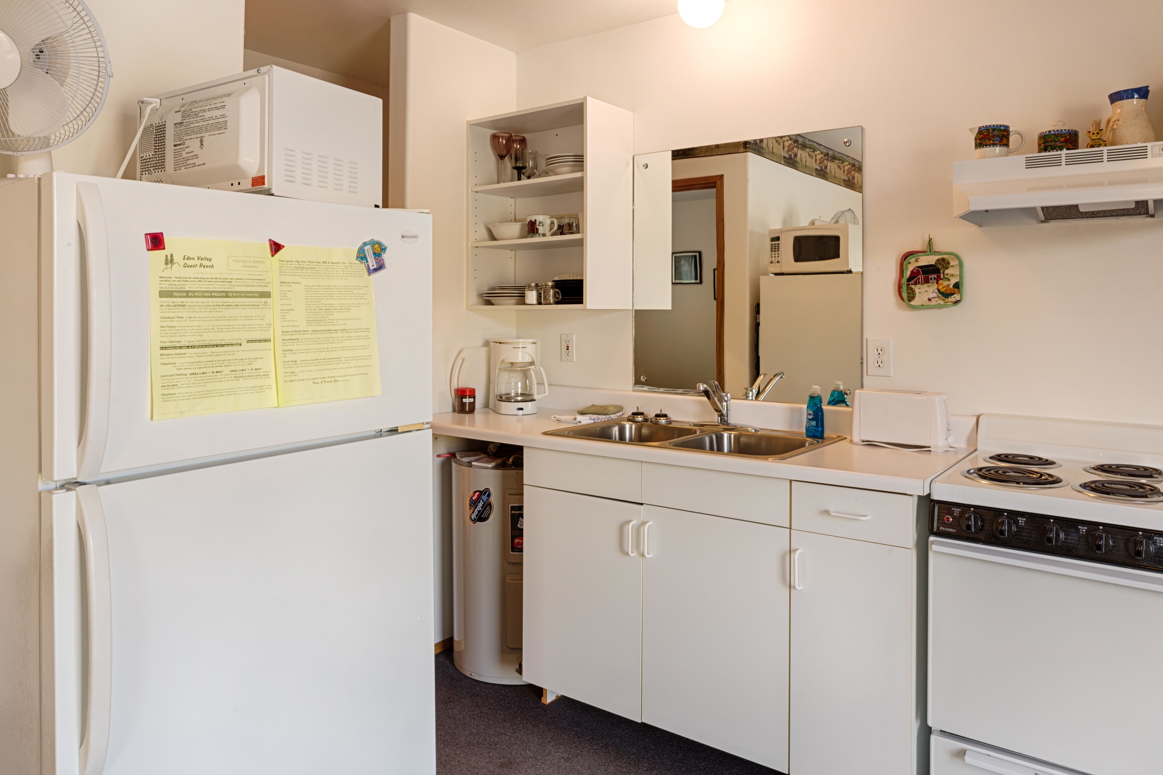 Une cuisine compacte équipée d’un réfrigérateur, d’un four à micro-ondes, d’une cuisinière, d’un évier et de placards.