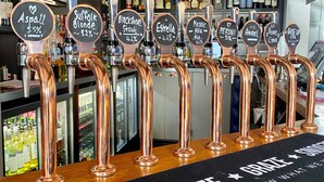 En bar med kranar i koppar, var och en märkt med namnet på en viss ölsort och alkoholhalten.