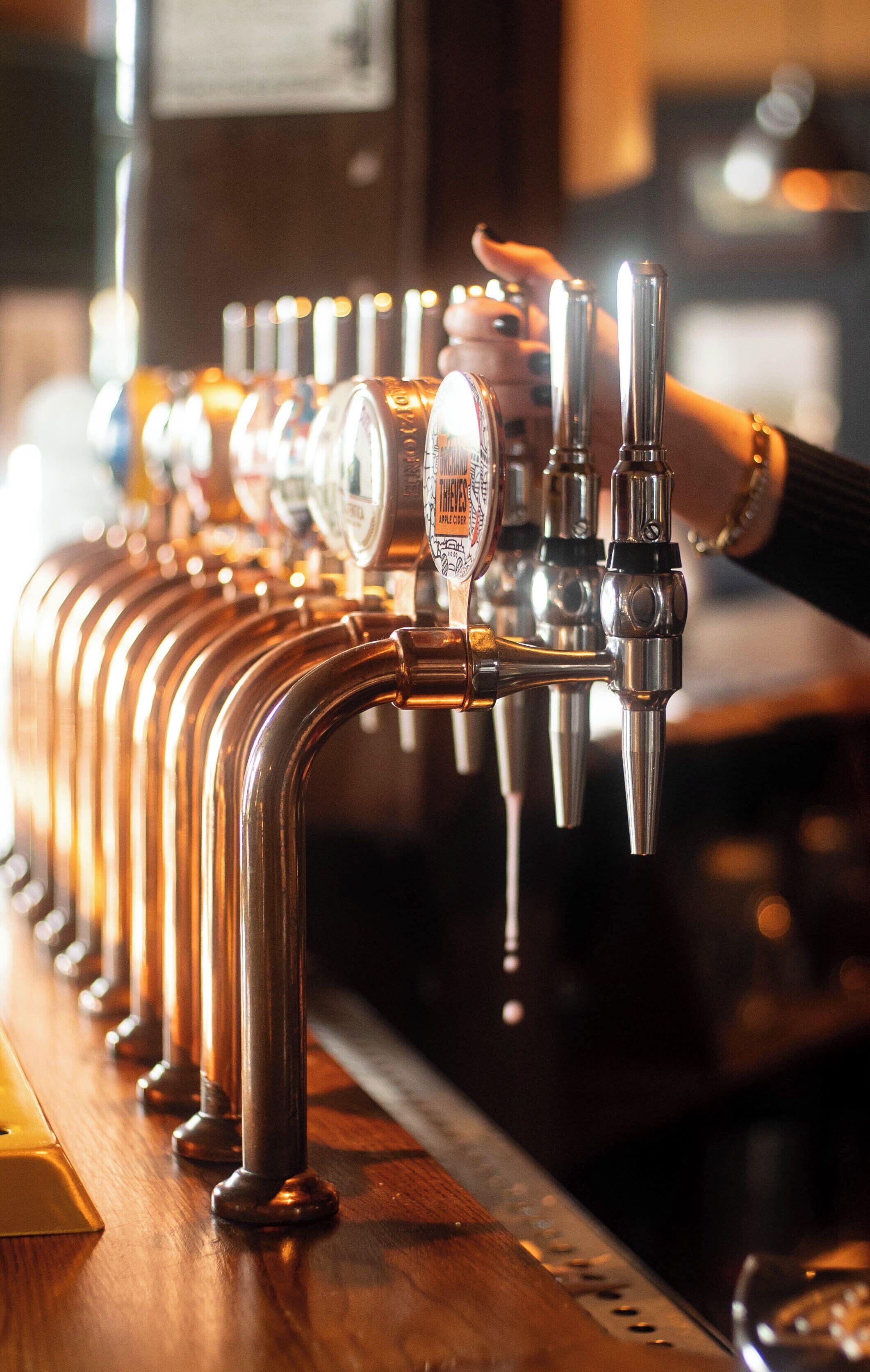 Fila de grifos de cerveza, uno con etiqueta que indica un tipo específico.