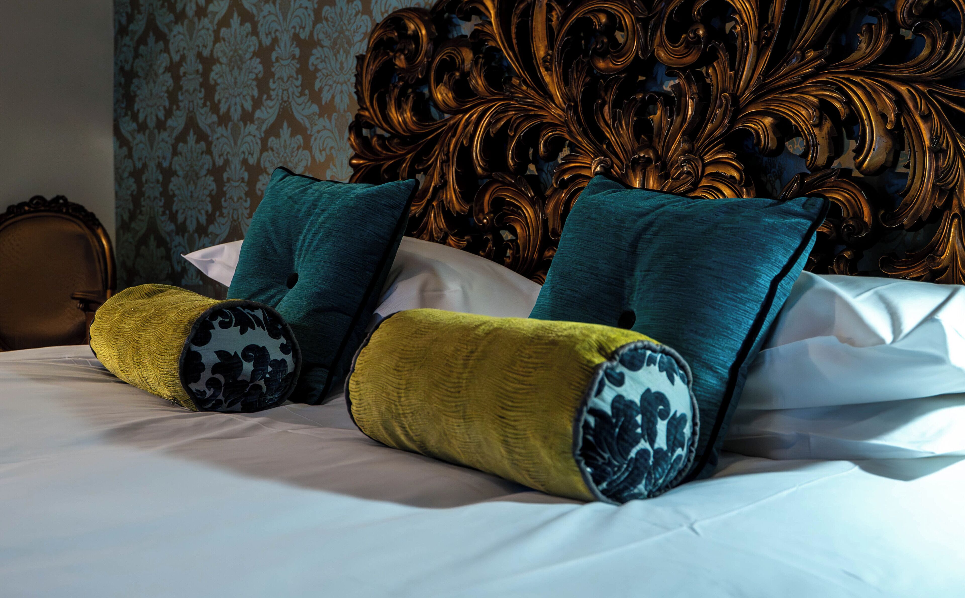 A bed with decorative pillows and a headboard with intricate carvings.