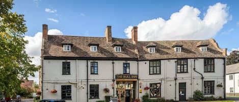 A traditional white building with a sign reading 'The Bull Inn' and a blue car parked in front.