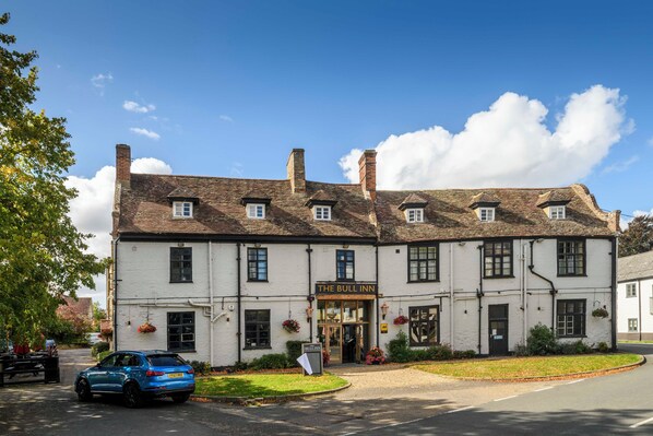 A traditional white building with a sign reading 'The Bull Inn' and a blue car parked in front. - The Bull Inn (Bury St Edmunds)