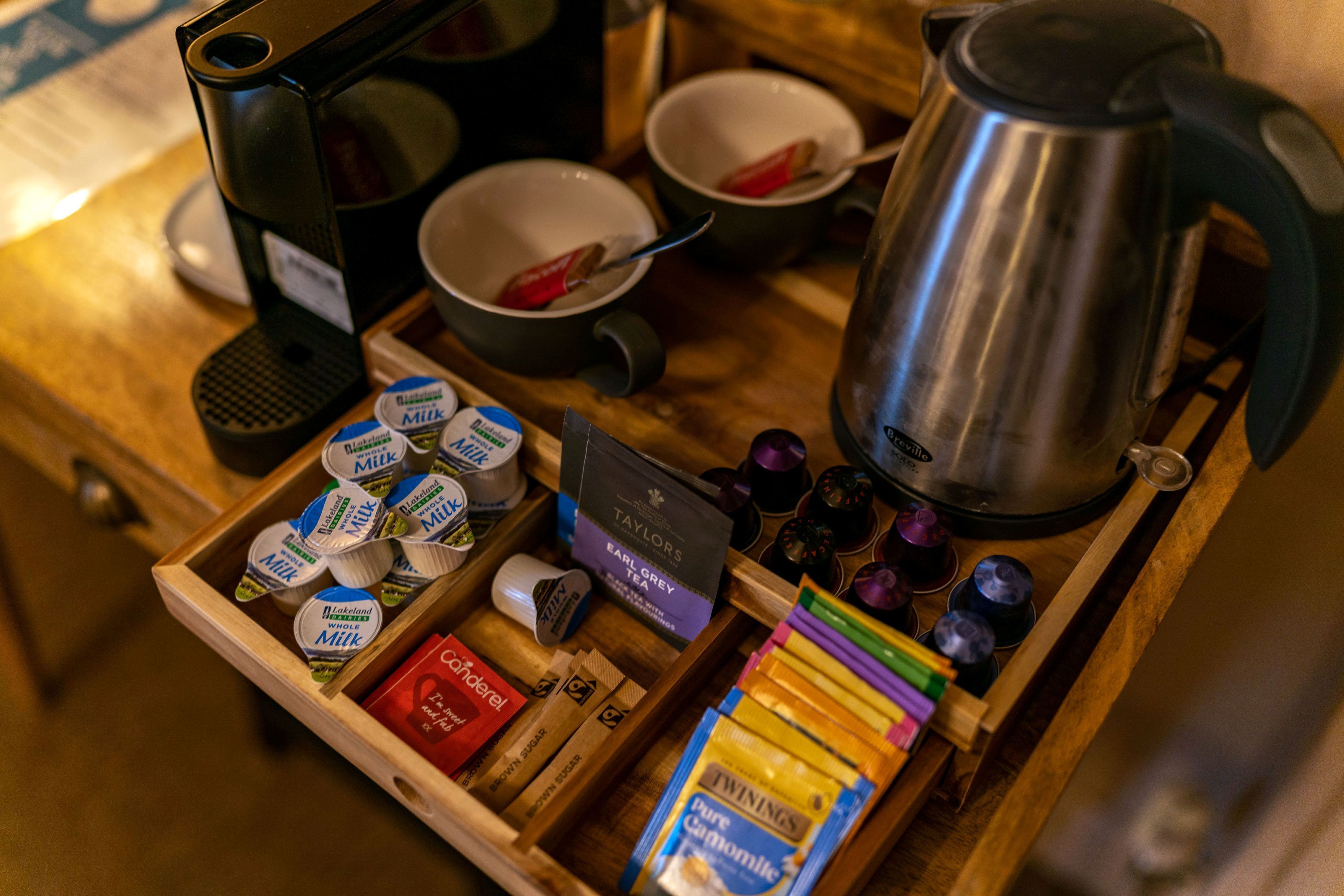 A wooden tray with various food items, including milk, tea, and snacks.