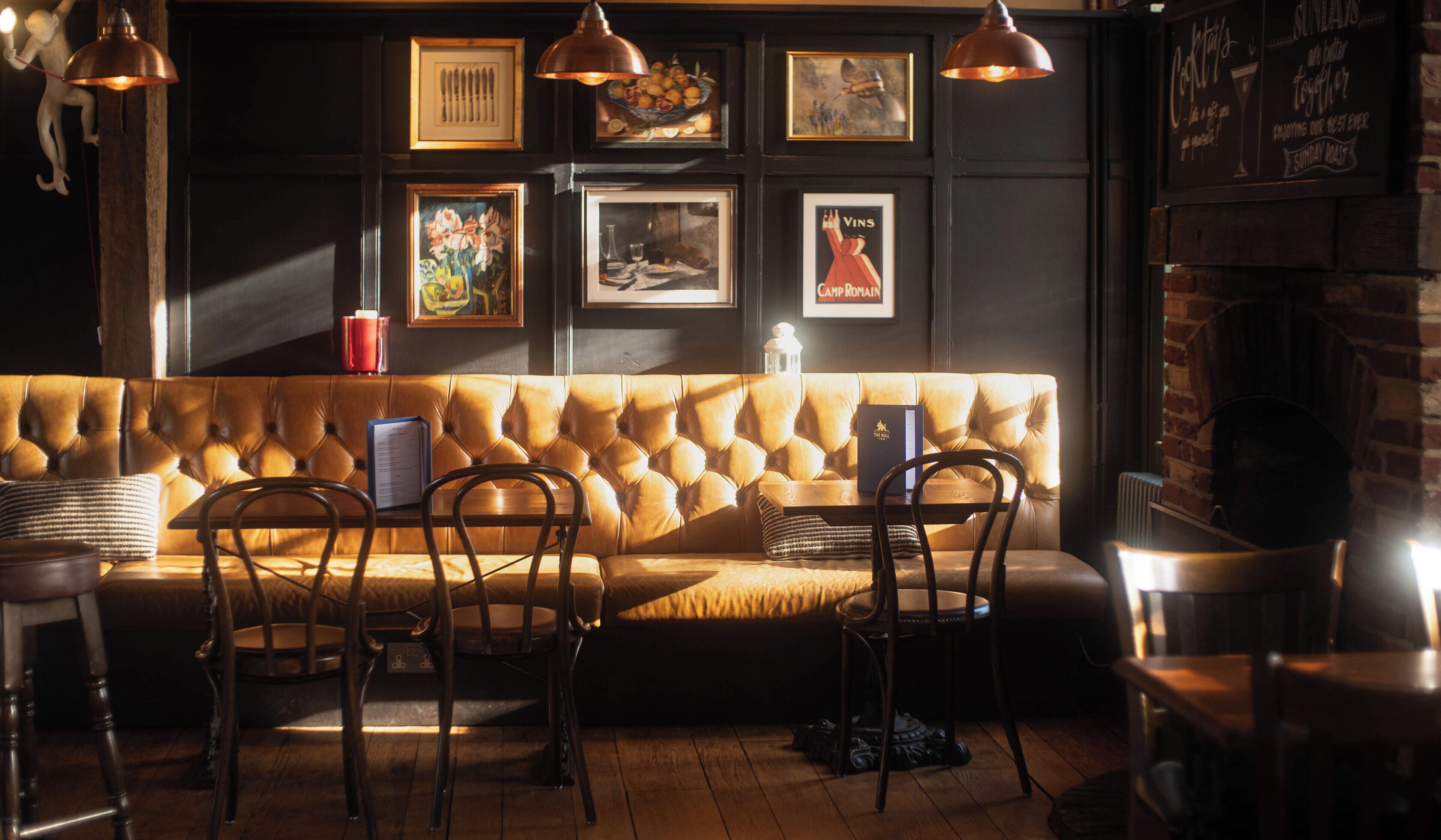 A cozy seating area with a tufted sofa, wooden chairs, and pendant lighting.