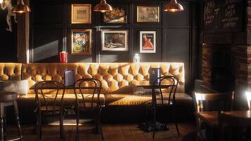 A cozy seating area with a tufted sofa, wooden chairs, and pendant lighting.