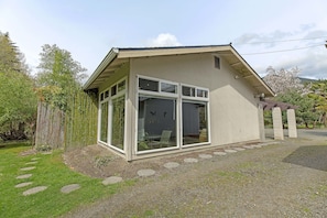 A modern house with large windows, a covered porch, and a stone pathway leading to the entrance.