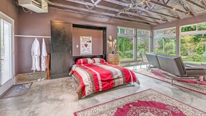 A bedroom with a large bed, a seating area, and a view of the outdoors. - Brinnon Gardens (Brinnon)