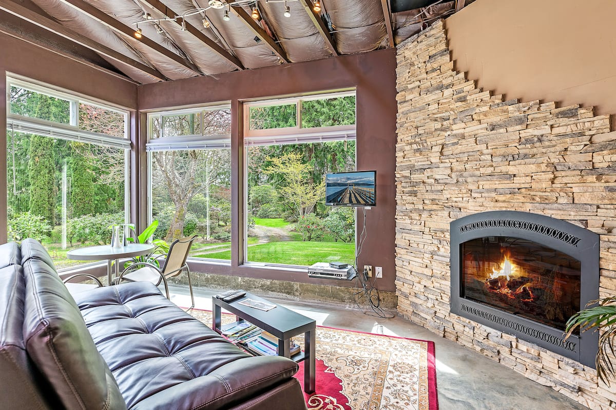 A cozy living room with a stone fireplace, large windows, and a comfortable seating area.