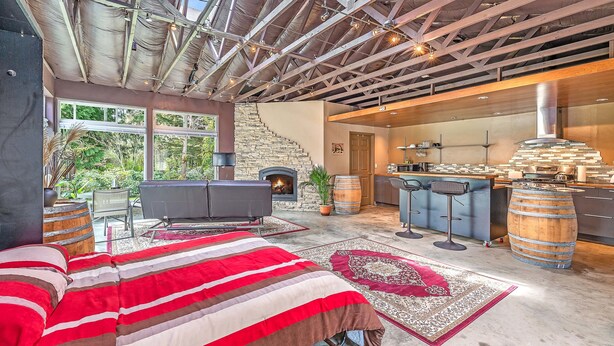 A spacious bedroom with a large bed, a fireplace, and a kitchen area visible through an open door. - Brinnon Gardens (Brinnon)