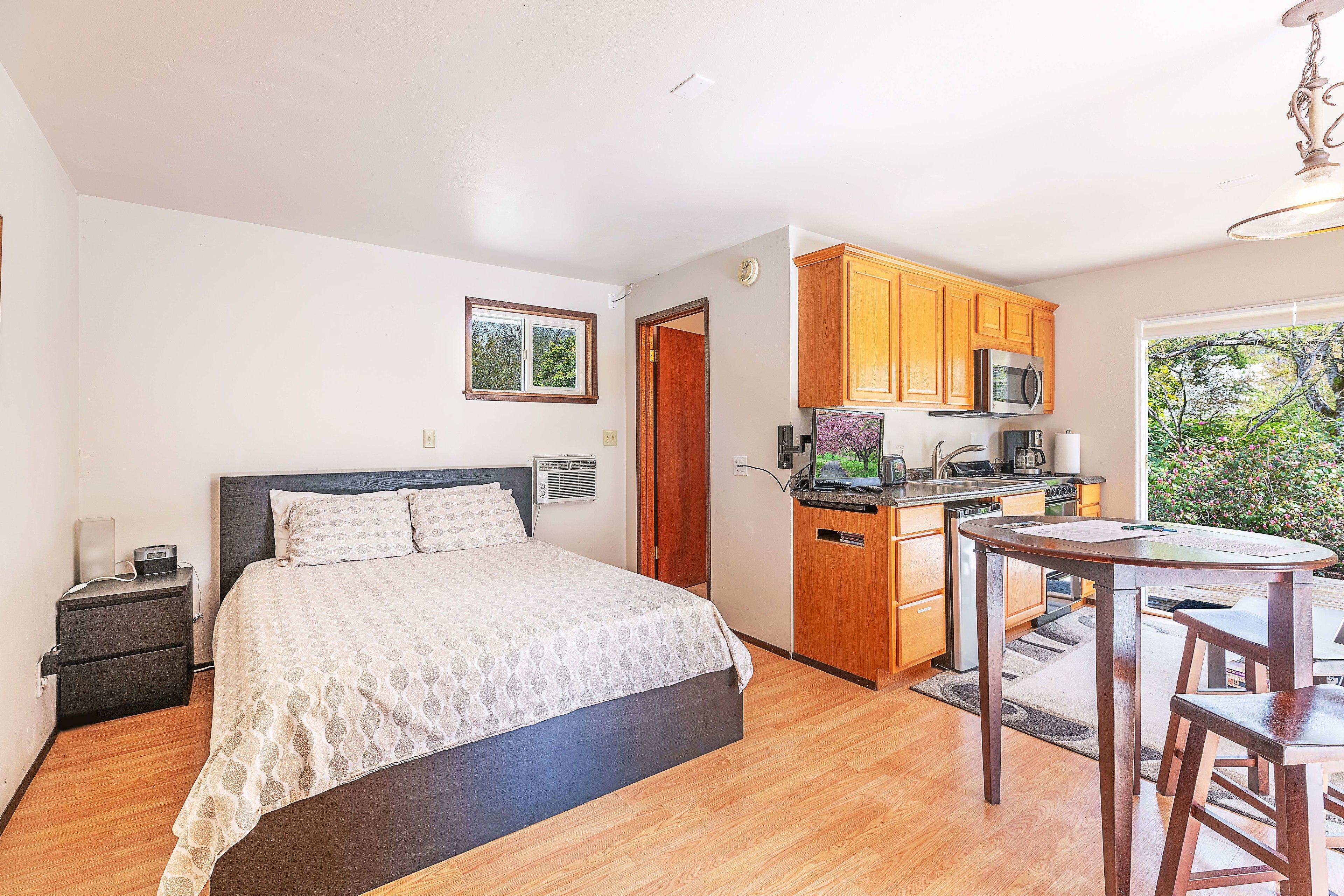 Une chambre avec un lit, une table de chevet et une petite kitchenette équipée d’un four à micro-ondes et d’un évier.