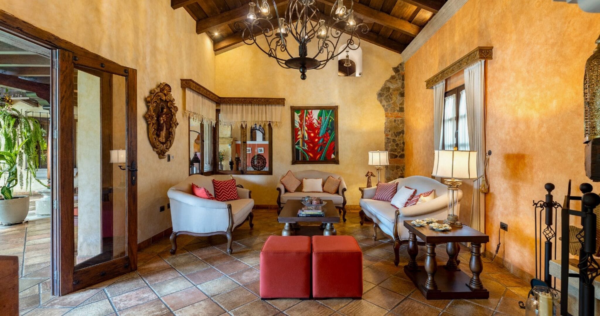 A spacious living room with a high ceiling, a chandelier, and a large painting.