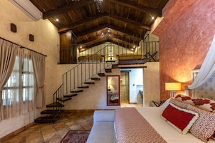 Un dormitorio con una cama grande, una escalera y vistas al baño.