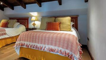 A hotel room with two beds, wooden flooring, and a ceiling with exposed beams.