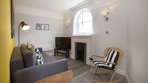 A living room with a sofa, a television, a fireplace, and a rocking chair. - Emperors Gate Residence by Allô Housing (London)