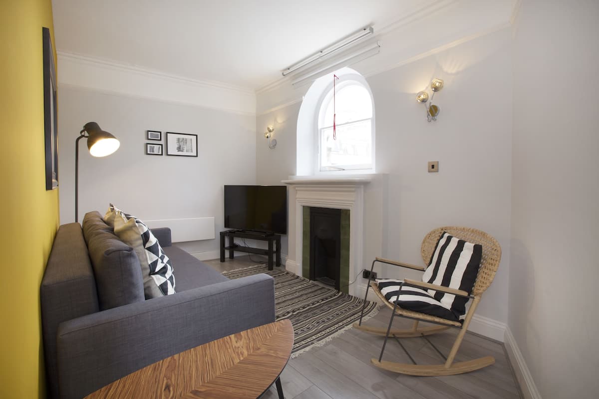 A living room with a sofa, a television, a fireplace, and a rocking chair.