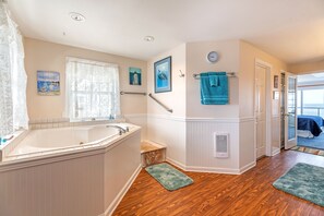 Un baño con bañera, ventana con vistas, toallero y puerta que conduce a otra habitación.