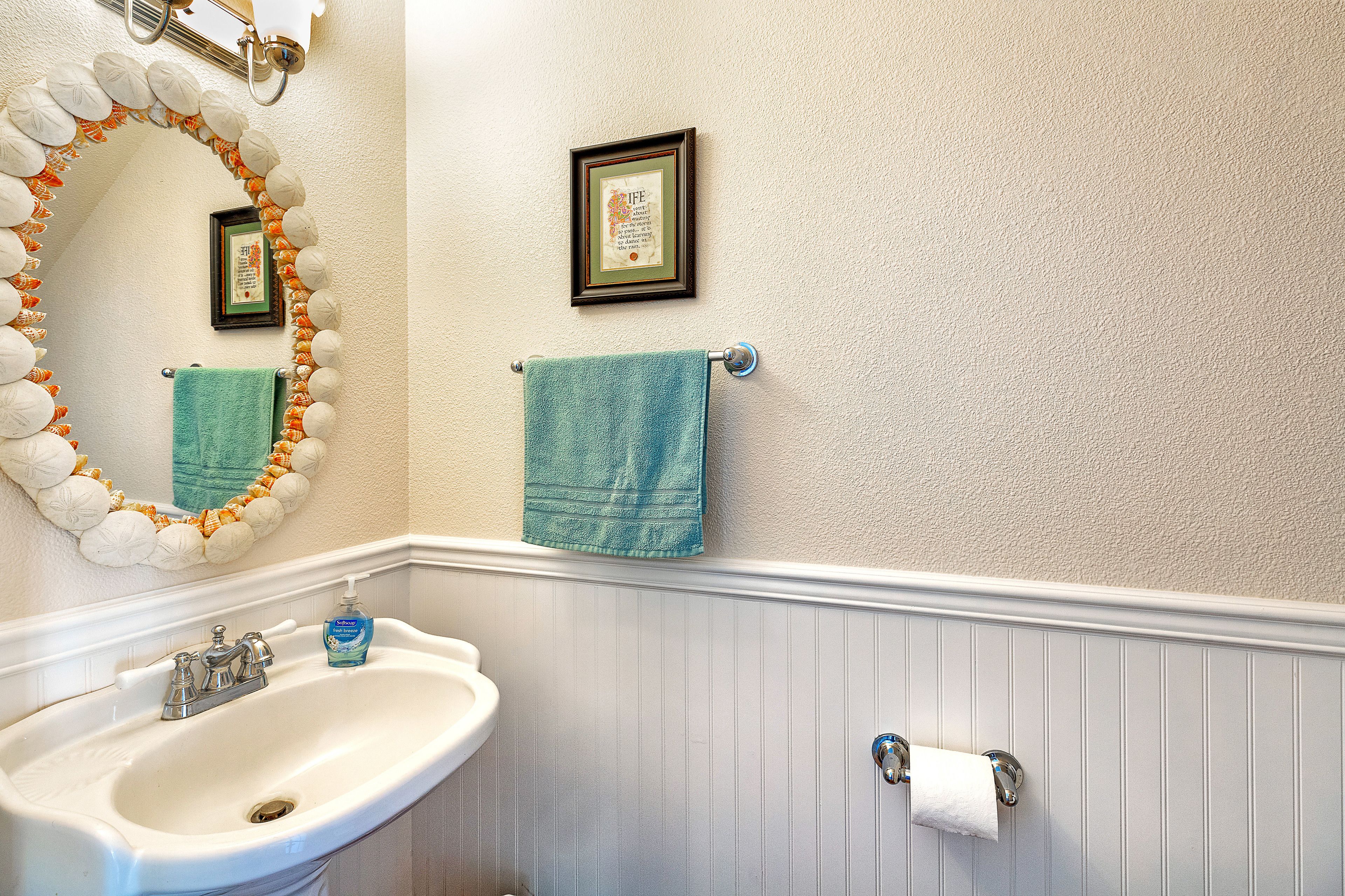 A bathroom with a white sink, a mirror with a decorative frame, and two towels hanging on towel bars.