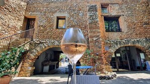 Un edificio de piedra con arcos y una gran escultura de copa de vino en el centro.