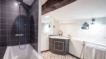 A bathroom with a bathtub, a shower, and a vanity with a mirror.