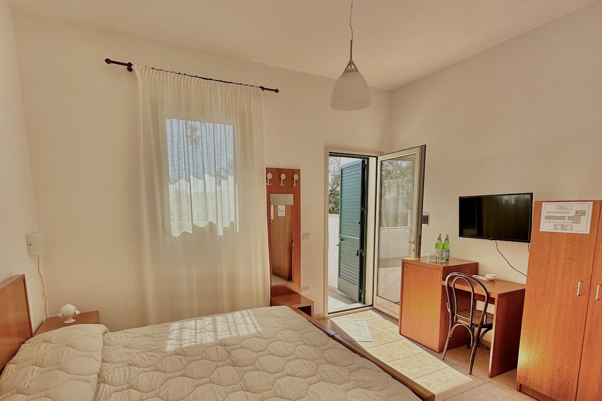 Un dormitorio con una cama grande, un escritorio, una silla, un armario y un televisor.
