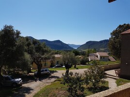 Un entorno rural con un camino de tierra, coches aparcados y casas con tejados de tejas.