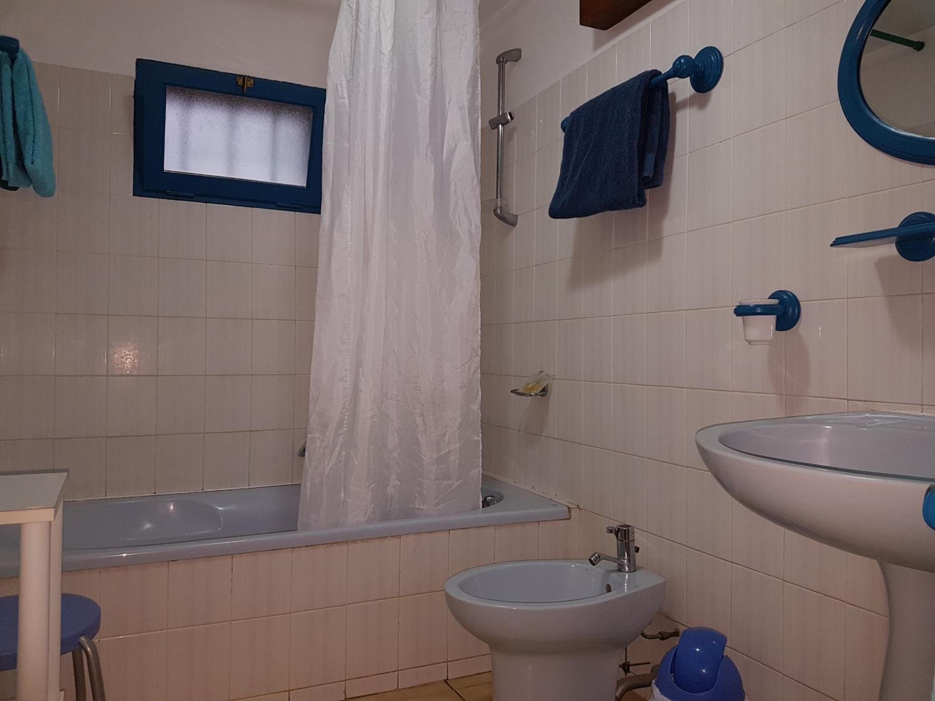 A bathroom with a bathtub, a sink, and a shower curtain.