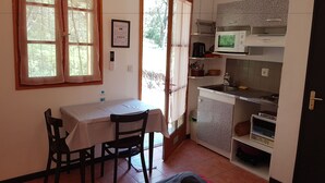 Cozinha compacta com mesa de jantar, cadeiras, micro-ondas e pia.