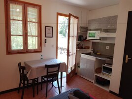 Una cocina compacta con una mesa de comedor, sillas, microondas y un lavamanos.