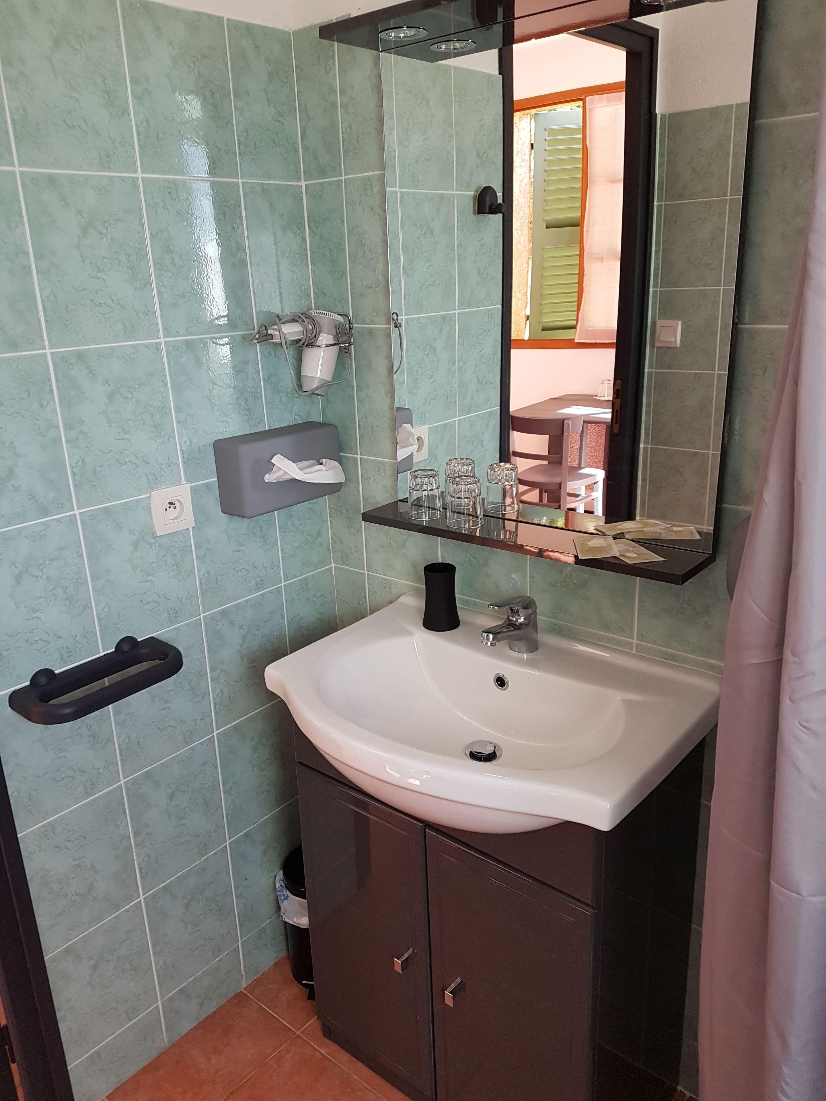 A bathroom with a white sink, a mirror, and a towel rack.